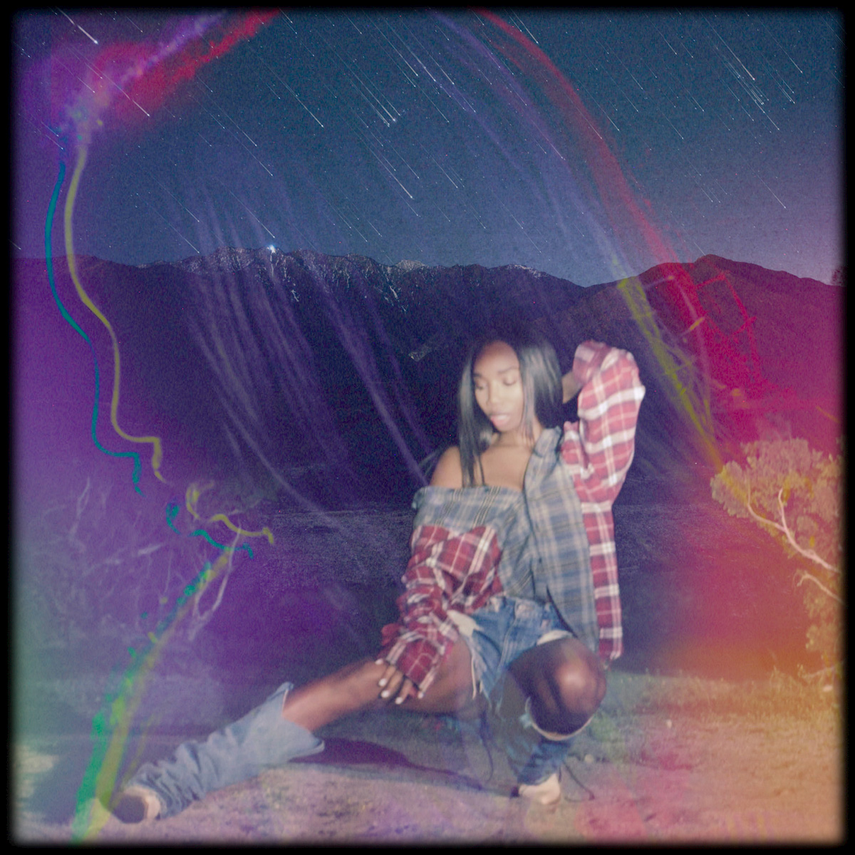 Amira crouched on a desert road at night through rainbow light leaks
